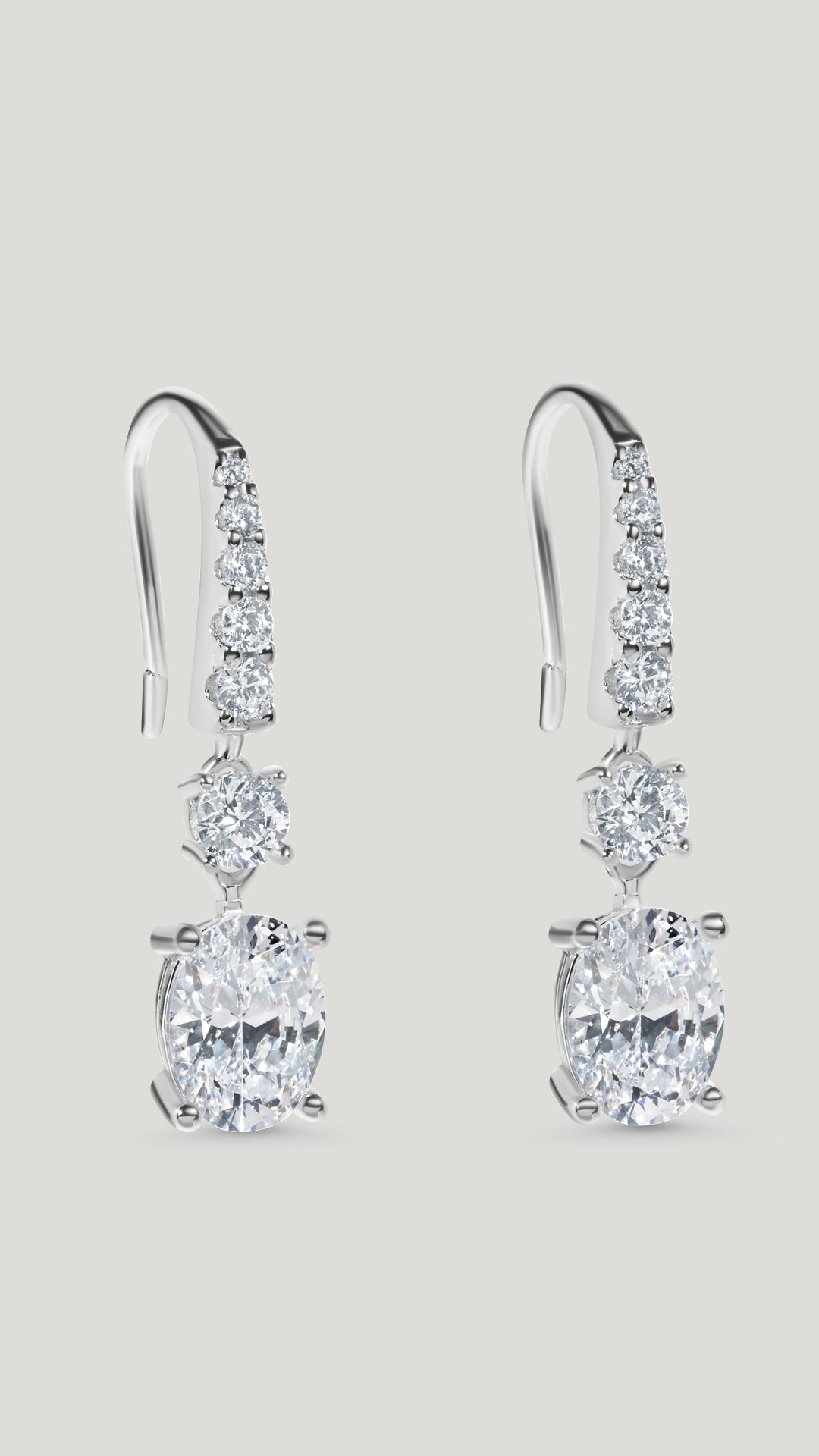 Staple pair of drop earrings for women featuring stunning oval cut stones accented with tapered round brilliant stones.