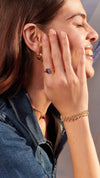 Lab-grown tanzanite stone in gold ring with layered bracelet for women