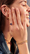 Lab-grown tanzanite stone in gold ring with layered bracelet and gold hoops for women